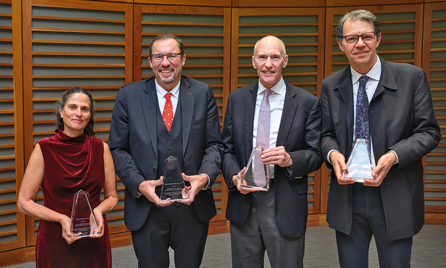 Four people holding awards