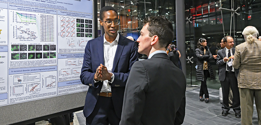 Photo of two men discussing in front of presentation 