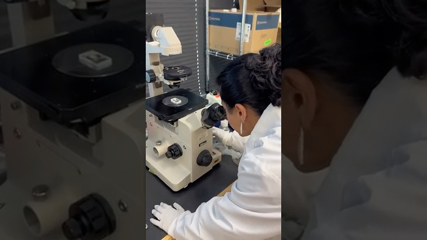 Picture of girl in white coat looking in microscope
