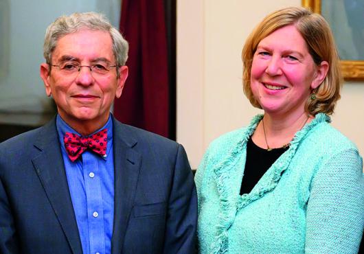 Man wearing a bow tie and woman in a cardigan smiling.