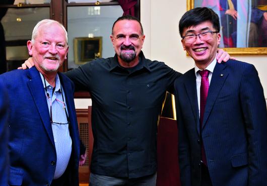 Three men with their arms around each other.