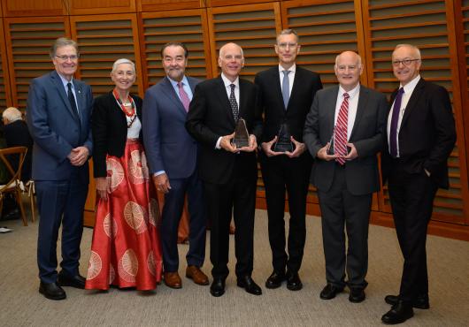 Photo of 7 people posing with two awards