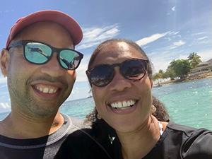 Two people wearing sunglasses taking a selfie in front of the ocean.