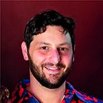 Man with a short beard and a flowered shirt.