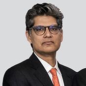 Man wearing a suit and glasses looking at the camera.