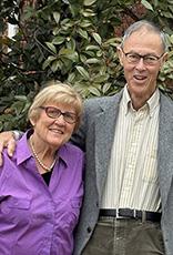 Woman and man standing in front of trees with their arms around each other.