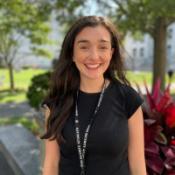 Woman smiling with trees in the background.