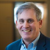 Man wearing a suit jacket smiling at the camera.