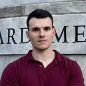 Man standing in front of marbel engraved with Harvard Medical School.
