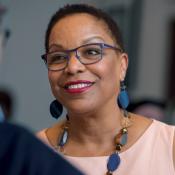 Woman in glasses smiling as she speaks to a man.